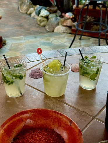 Three refreshing mint drinks with ice on a tiled outdoor table.