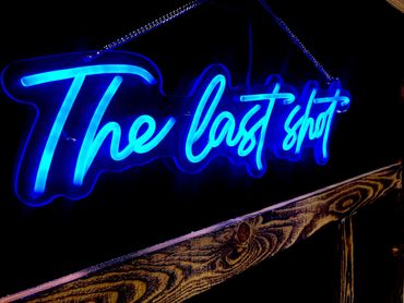 Blue neon sign reading 'The last shot' hanging on a wall.