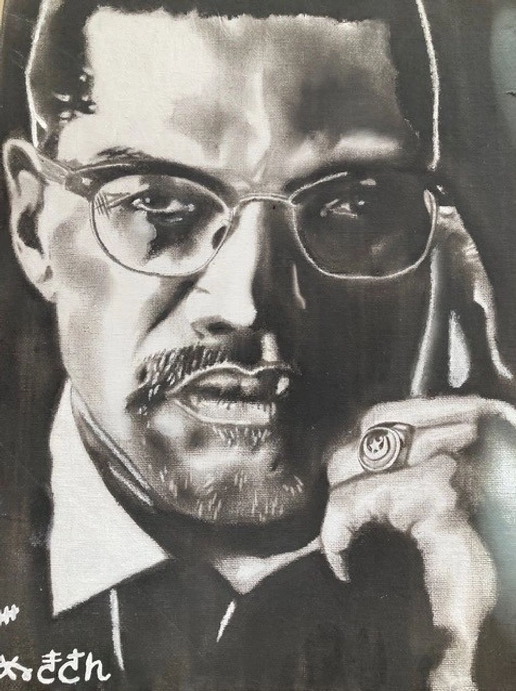 Black and white portrait of a man with glasses and a ring on his finger.