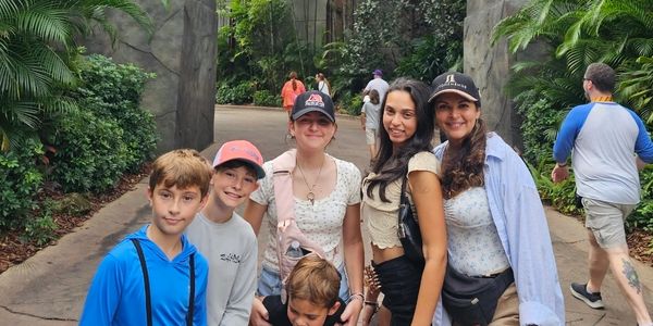 A group of five people smiling outdoors surrounded by greenery.