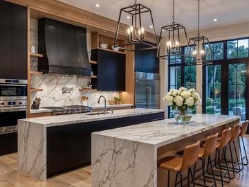 Modern luxury kitchen with waterfall marble islands and black cabinetry.