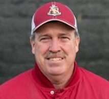 Man wearing a red baseball jacket and cap with a sports logo.