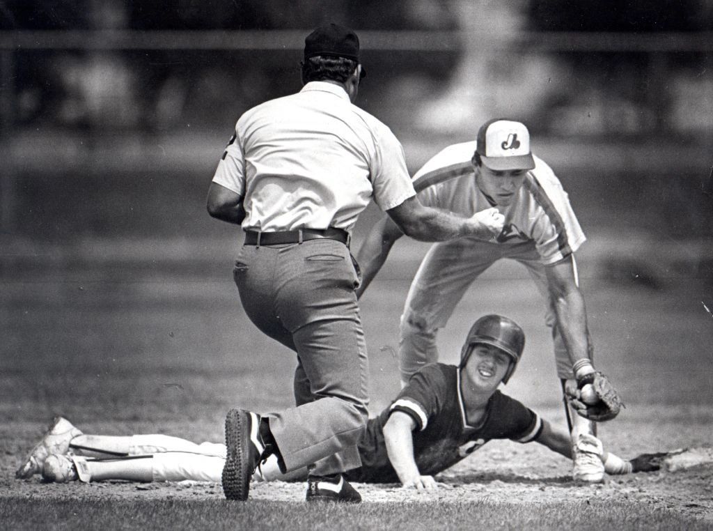 Baseball player slides into a base as the fielder tags him with the ball.