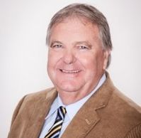 Smiling man in a brown corduroy jacket with a striped tie.