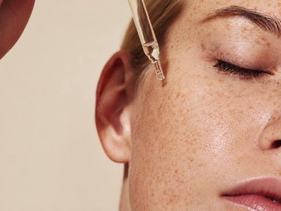 Applying facial serum with a dropper near the eye.