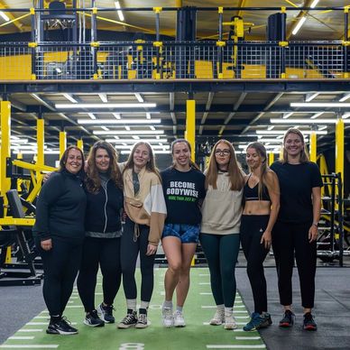 Group of seven women posing in a gym.