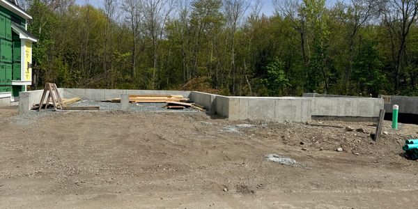 Construction site with concrete foundation and surrounding forest.