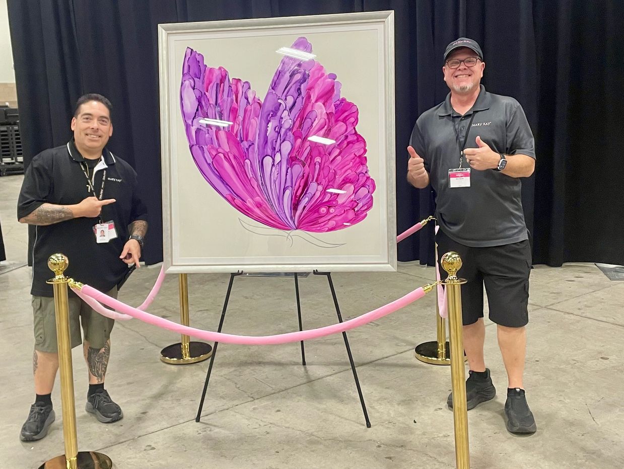 Two men posing with a butterfly artwork.