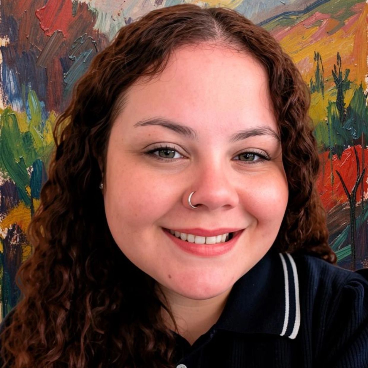 Smiling woman with curly hair and nose ring in front of a colorful abstract painting.