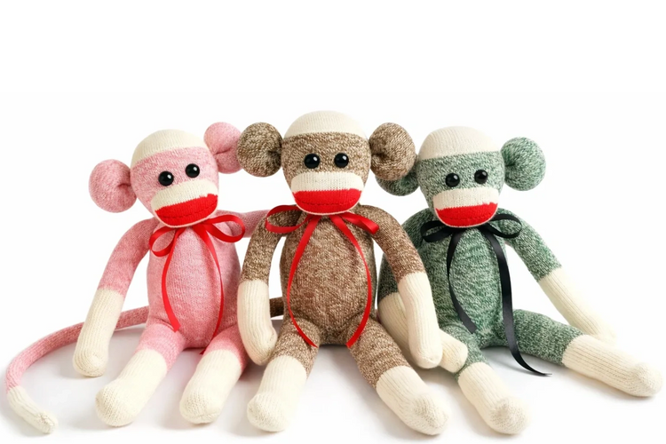 Three handmade sock monkeys sitting together on a white background, showcasing personalized.