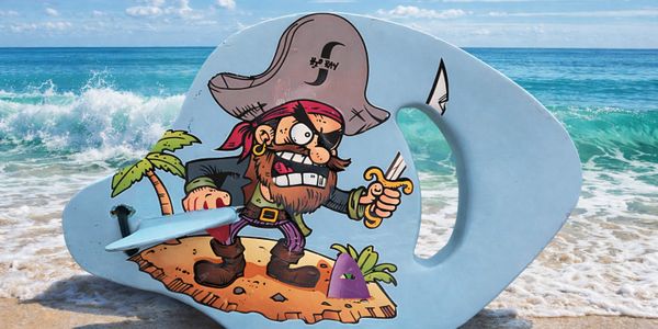 Colorful pirate illustration on a blue bodyboard at the beach shore.