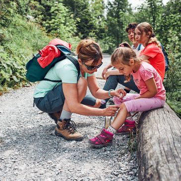 Mother dressing the wound on her little daughter's knee with medicine in spray