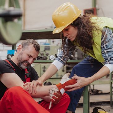 Woman is helping her colleague after accident in factory