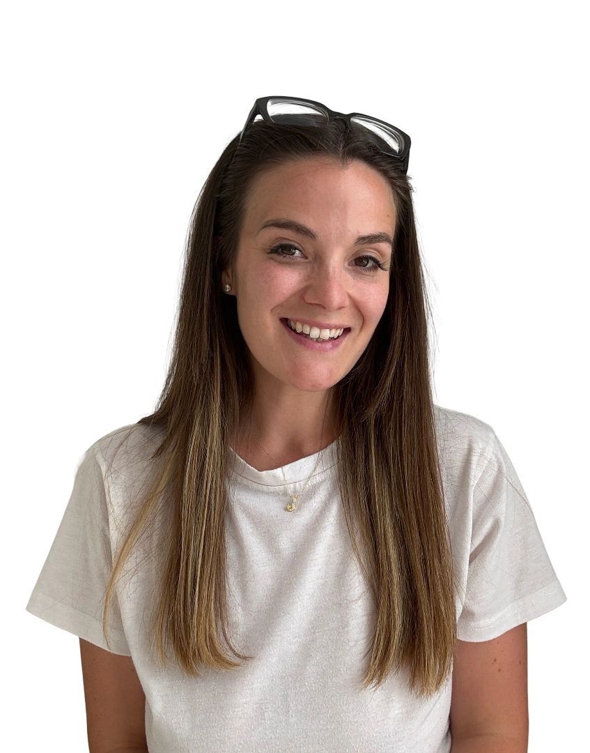 Smiling woman with long hair and glasses on head wearing a white t-shirt.