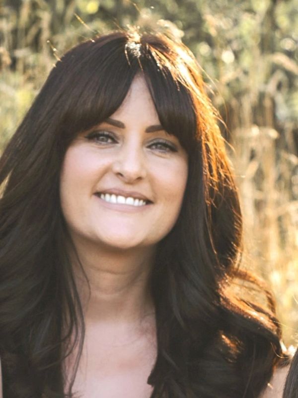 Smiling woman with dark hair outdoors.