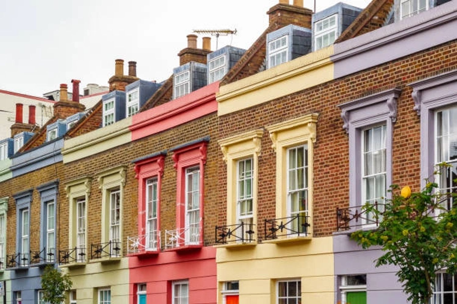 Row of colorful terraced houses with brick facades and decorative window frames.