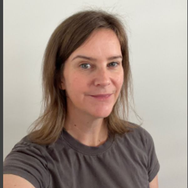 Woman with shoulder-length brown hair and gray shirt.
