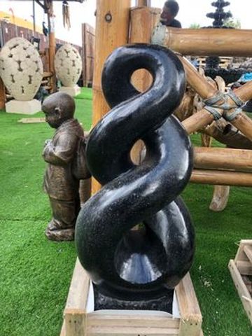 Black twisted abstract sculpture in a wooden box.