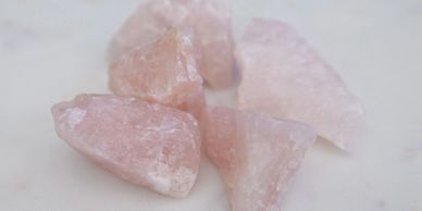 Several pink rose quartz crystals on a white surface.