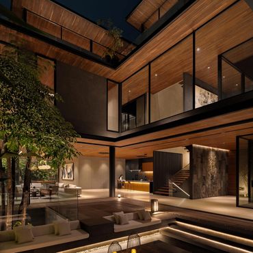Luxurious modern home with warm wood accents and elegant outdoor seating illuminated at night.