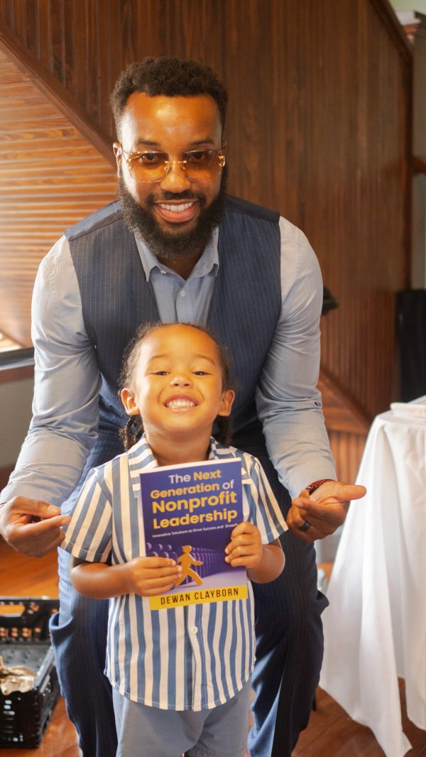 Smiling man and child holding a nonprofit leadership book.