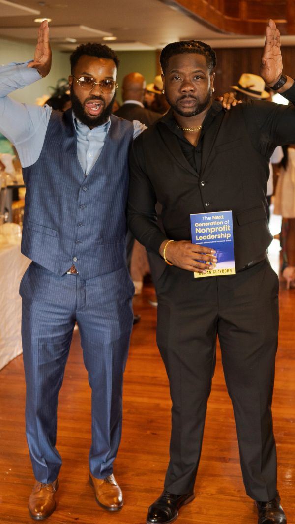 Two men in suits posing with one holding a book on nonprofit leadership.