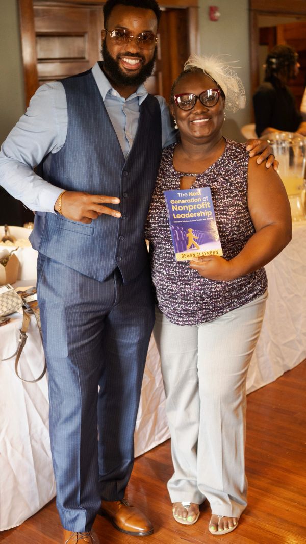Two people smiling, one holding a book titled 'The Next Generation of Nonprofit Leadership'.