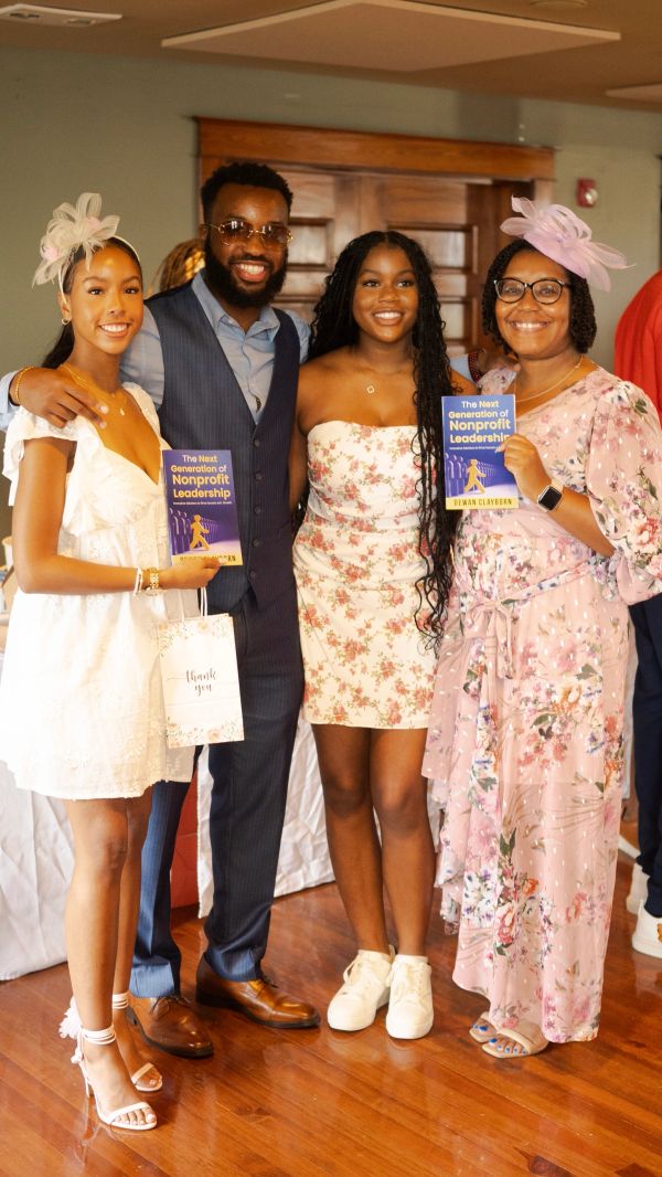 Four people smiling at an event, two holding books titled 'The Next Generation of Nonprofit Leadership.'