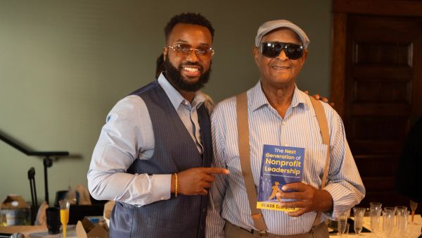Two men smiling, one holding a book on nonprofit leadership.