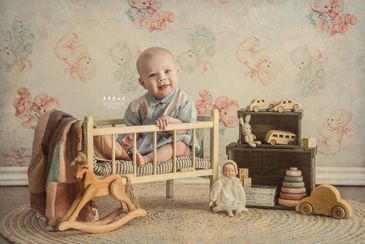 baby boy sitting in crib vintage toys and backdrop