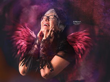 Empowering photo of a woman laughing with vibrant wings and dramatic lighting