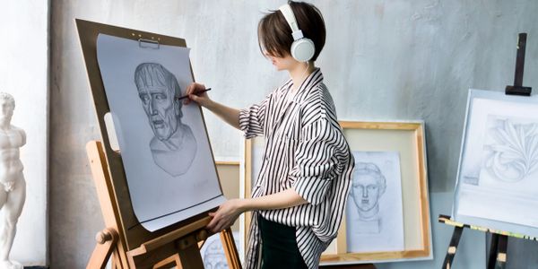 person drawing on a big sheet of paper, following a model