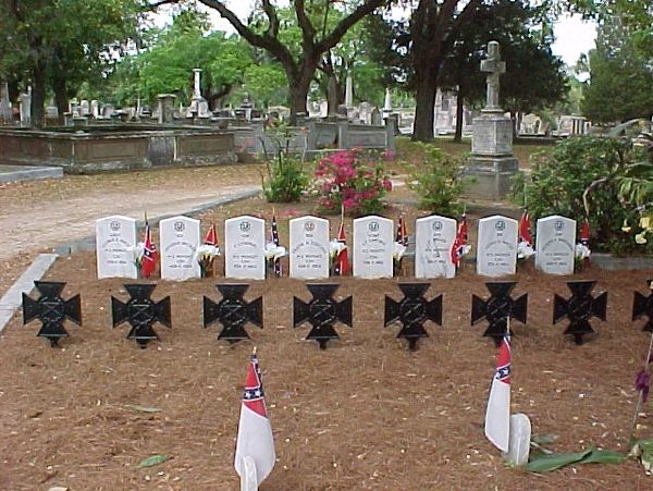 Historic Confederate graves with tombstones and flags in a quiet cemetery.