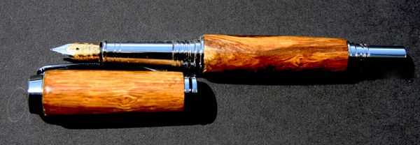 Elegant wooden fountain pen with cap removed, displaying gold nib.