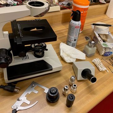 Work bench with disassembled microscope being serviced