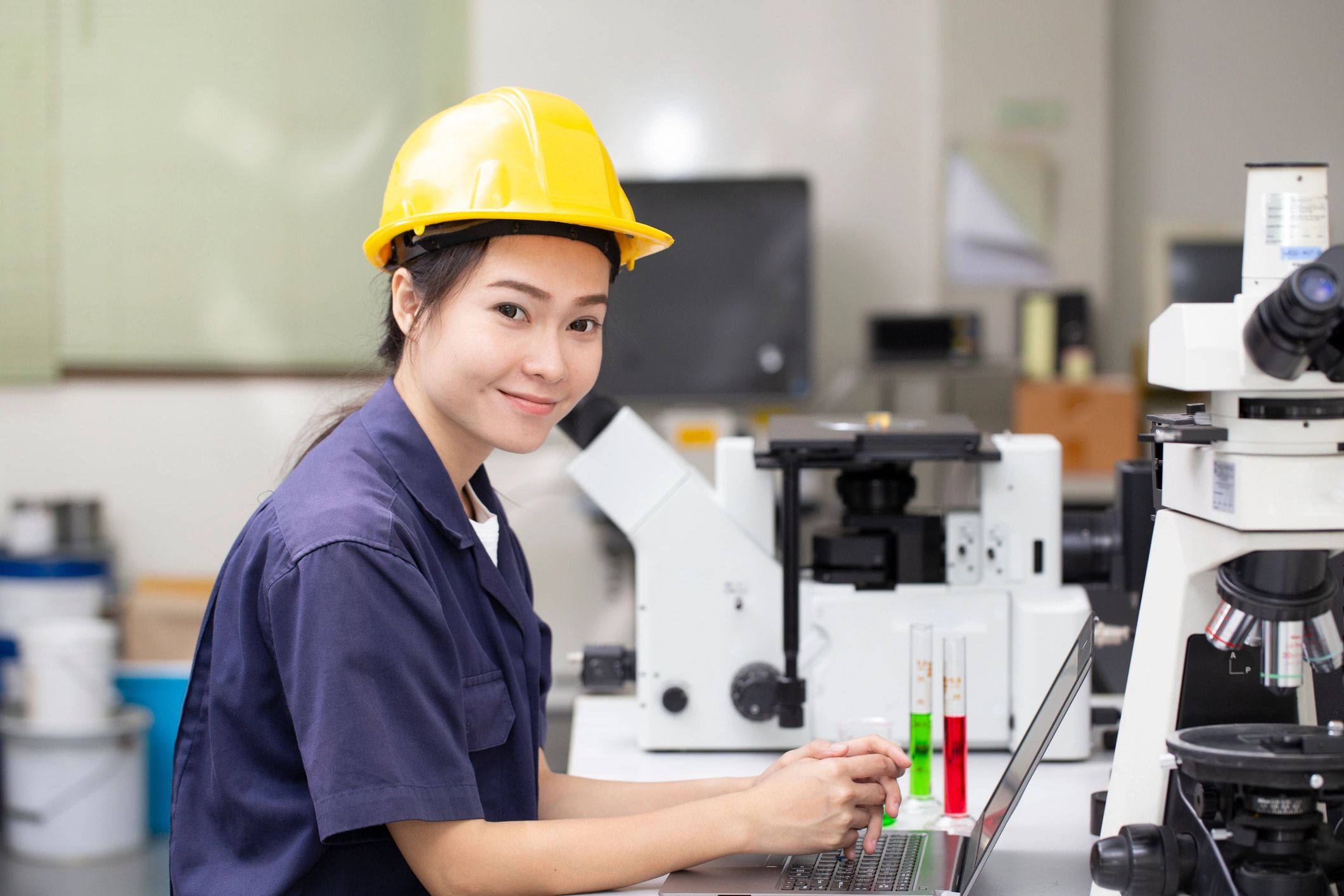 Industrial Technician with hard hat in lab with two microscopes