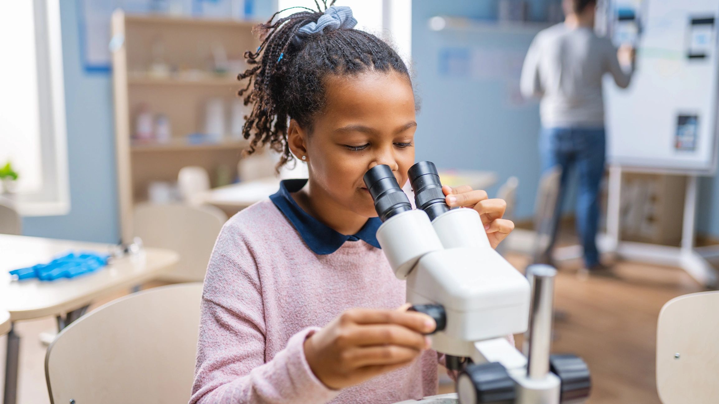 Young girl using a stereo microscope 