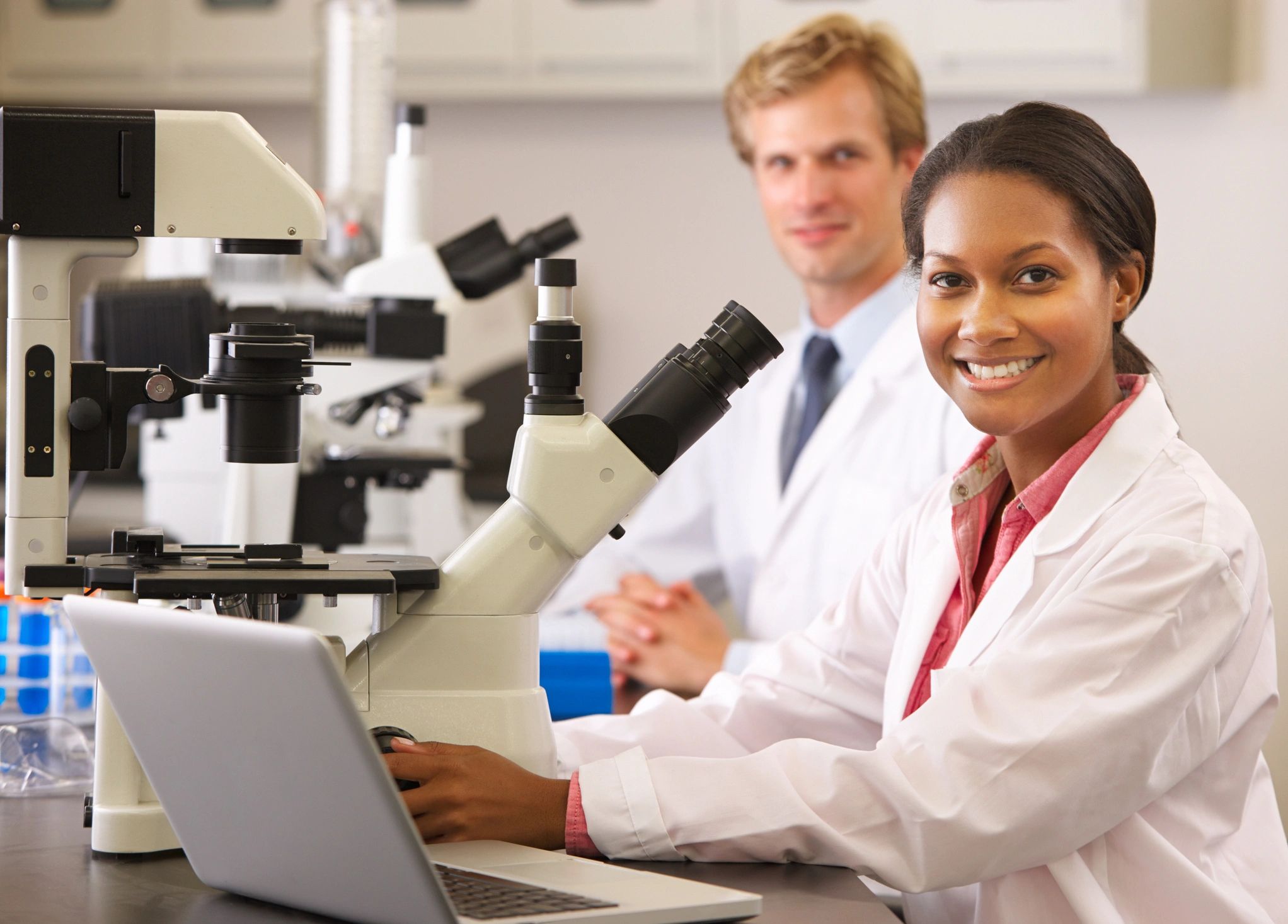 Smiling, Happy lab technicians in lab with several microscopes