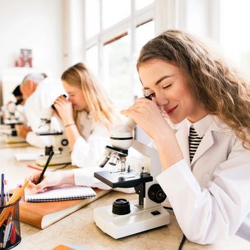 Female students using monocular compound microscopes