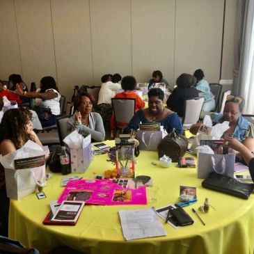 Women gathered around a yellow table at a group event.