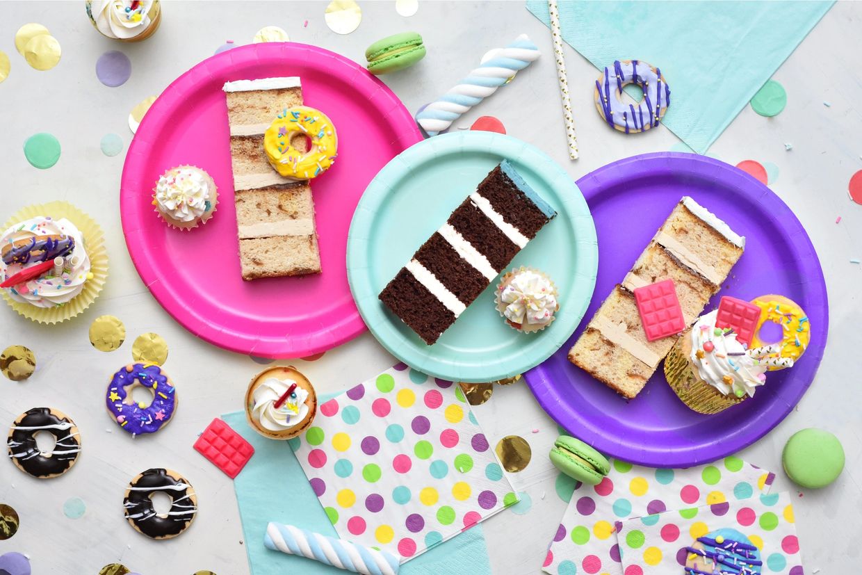 Vanilla birthday cake slice, chocolate cake slice and cupcakes on plates Photo by Deva Williamson