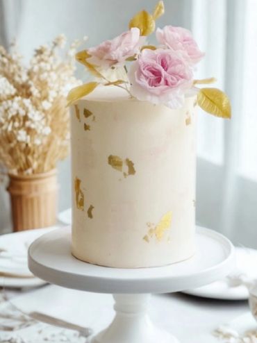 6” tall vanilla cake with edible gold foil and wafer paper Juliet roses. Gold leaves