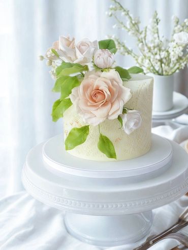 Birthday cake sitting on stand with gold foil application, stenciling, and sugar flowers