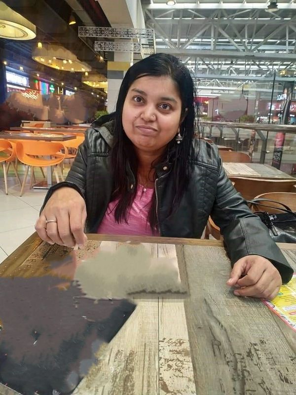 Woman in a black jacket sitting at a table in a restaurant.