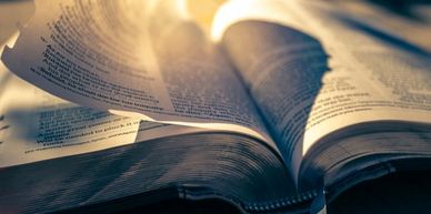 Bible open with page turning and light at top of pages.