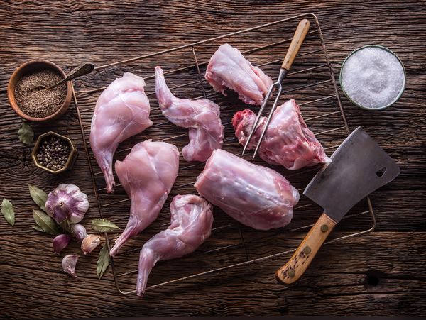 Cut raw rabbit meat with spices and cleaver.