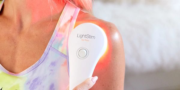 Person holding LightStim for pain personal device on their shoulder.