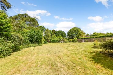 Large garden mainly laid to lawn with mature trees and shrubs.