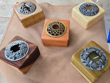 Five decorative wooden candle holders with intricate metal designs.