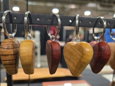 Wooden heart-shaped keychains hanging on a display rack.